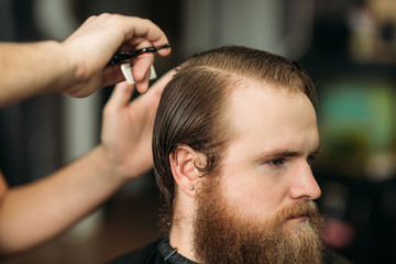 Barber using scissors and comb in barbershop