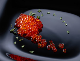 Red caviar on a black plate.