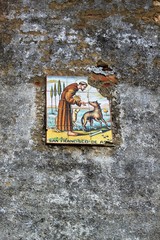 bild von franz von assisi auf fliese gemalt an einer alten steinernen mauer/zerfallenes heiligenbildnis, schutzpatron der tiere/hand gemalt auf keramik, hl. franziskus 