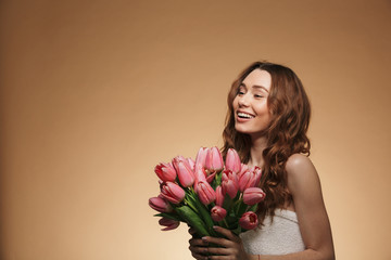 Pretty young woman standing isolated holding tulips