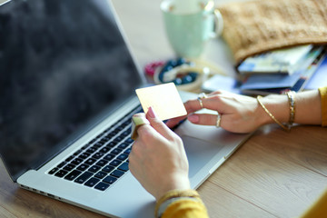 Young woman holding credit card and using laptop computer. Online shopping concept