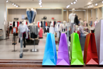 Naklejka premium Paper shopping bags with shopping and gift, on the floor against with blurred clothes shop for display or montage your products