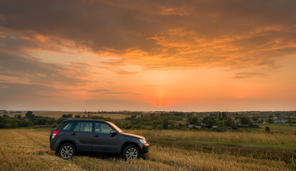Fototapeta na wymiar Road car on a field at sunset
