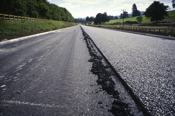 A new road under construction being surfaced with tarmac