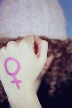 Tributo al feminismo con una mujer joven que lleva pintado un símbolo femenino en su mano