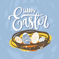 Happy Easter elegant lettering or holiday wish handwritten with cursive calligraphic font and eggs lying in nest on blue background