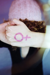Tributo al feminismo con una mujer joven que lleva pintado un símbolo femenino en su mano