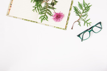 notebook,glasses and flower.flat lay.white background.copy space