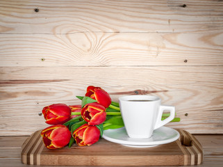 White cup of coffee and red tulips on the light wooden background. Mother's Day and Women's Day celebration