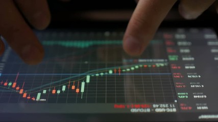 Stock market, trading online, trader working with tablet on stockmarket trading floor. Man touching screen, browse foreign exchange market data, chart. Forex. Crypto currency. Bitcoin cryptocurrency.