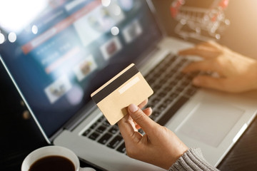 Shopping online concept. Woman holding gold credit card in hand for online shopping by using laptop...