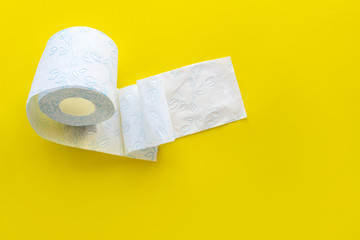 Roll of white toilet paper on a yellow background with empty space.