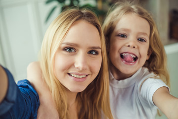 Smiling and happy mom and daughter are hugging each other at home on the couch. Mom and daughter ...