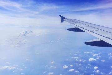 Scenery from airplane 's window viewing wing of airplane , white clouds and blue sky