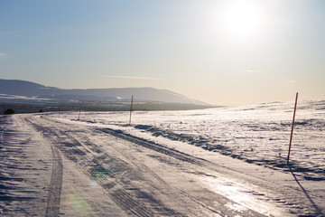 A beautiful white snowy road in central Norway with a red safety poles. Minimalist winter scenery un northern Europe.