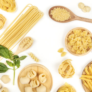 Overhead square photo of different types of pasta with basil on white with copy space