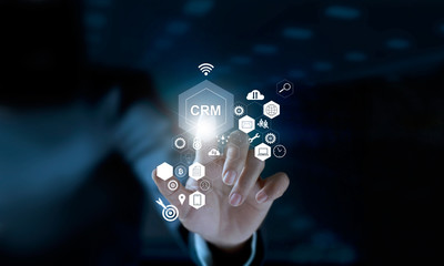 Businessman touching icon CRM on modern virtual interface. Customer relationship management (CRM) concept.