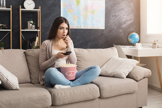 Young woman sitting on the couch and watching tv