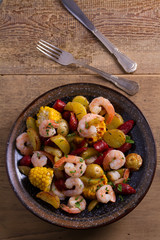 Shrimps with sausages, new potatoes and sweet corn. One sheet pan shrimps with sausages and vegetables. View from above, top