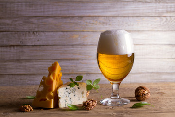 Bière et fromage. Verre de bière au fromage, noix et basilic sur fond de bois. Concept de bière et de nourriture