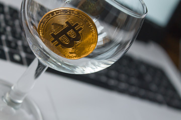 golden bitcoin in a glass on laptop background