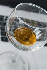 golden bitcoin in a glass on laptop background