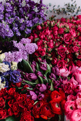 Bunch of fresh blossoming flowers at the florist shop: roses, ranunculus, tulips, eucalyptus, eustoma, mattiolas and carnations in lavender purple and red colors