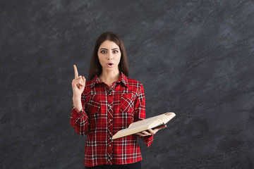 Serious girl student holding books pointing finger up