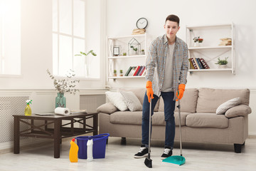 Young man cleaning home, sweeping