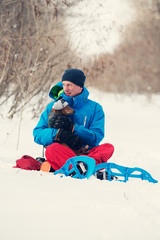Fototapeta na wymiar Traveler in snowshoes hugging funny dog