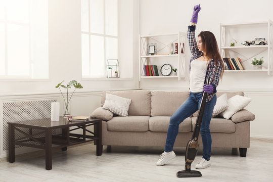 Happy woman cleaning home with vacuum cleaner
