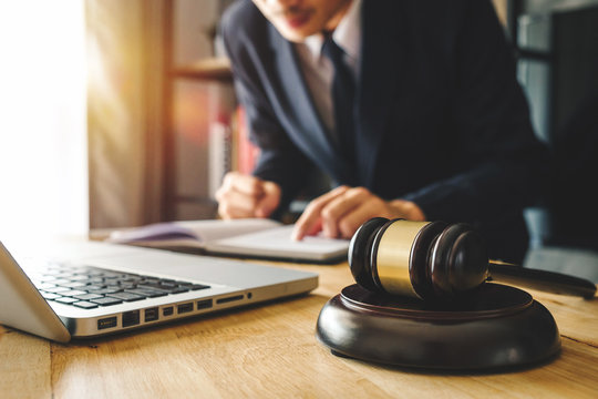 Justice And Law Concept.Male Judge In A Courtroom  The Gavel,working With Digital Tablet Computer On Wood Table In Morning Light 
