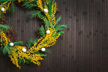 Wreath of mimosa with eggs on a brown background