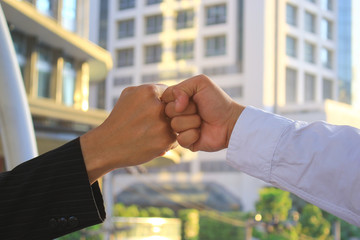 Two Business people giving fist bump after successful negotiations on bokeh and sunlight background