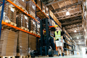 Warehouse worker doing logistics work with forklift loader