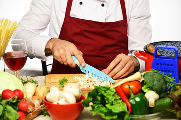 Male hands cuts mushroom with knife, apron on background.
