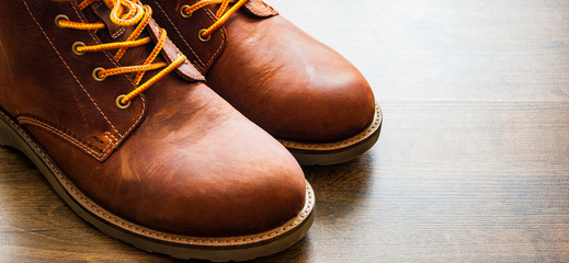 brown leather boots shoes on the brown wooden table background.with copy space. - Powered by Adobe