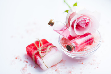 Spa and natural cosmetics concept. Set of sea salt, rose, natural clay ,shea oil, glass bottles and other spa treatment tools on the white background. Top view. Space for a text. Close up.