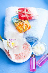 Spa and natural cosmetics concept. Set of sea salt, orchid, natural clay ,shea oil, glass bottles and other spa treatment tools on the blue wooden background. Top view. Space for a text. Close up.