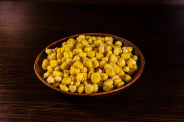 Ceramic plate with canned corn seeds on wooden table