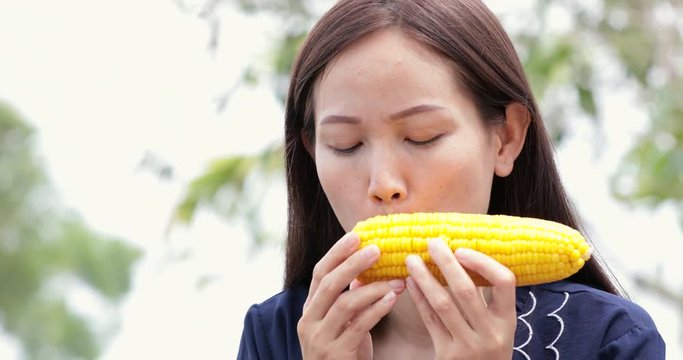 Asian woman eats boiled corn