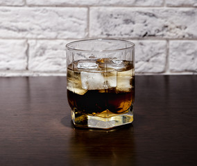 A glass of whiskey and ice on the table.
