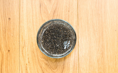 Glass of Soaked Chia Seeds Against Wooden Table, Shown from Above