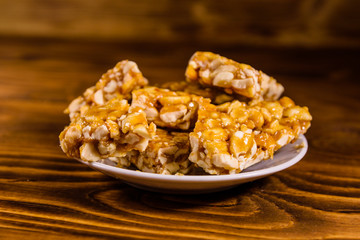 Ceramic plate with peanut brittles on wooden table.