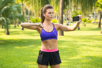 Woman watching online a fitness lesson during her workout in the park