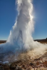 Erupting geyser in sunlight