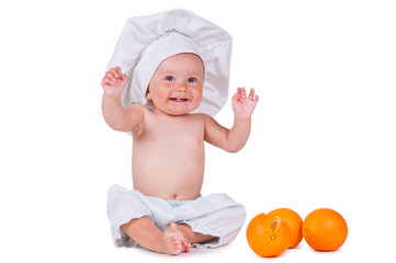 A small child eats an orange slice in a chef suit on a white background.