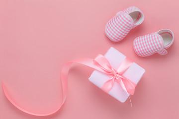 Top view aerial image of decoration Happy mothers day holiday background concept.Flat lay gift box with baby shoes on modern beautiful pink paper at home office desk.Free space for creative design.