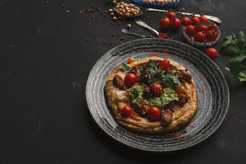 Hummus with vegetables and seafood on black background
