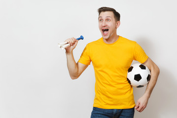 Inspired young fun cheerful European man, fan or player in yellow uniform hold soccer ball, pipe,...